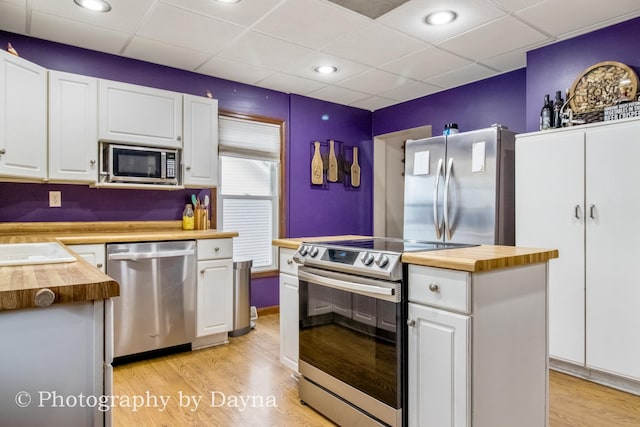 kitchen featuring white cabinets, wooden counters, appliances with stainless steel finishes, and a drop ceiling