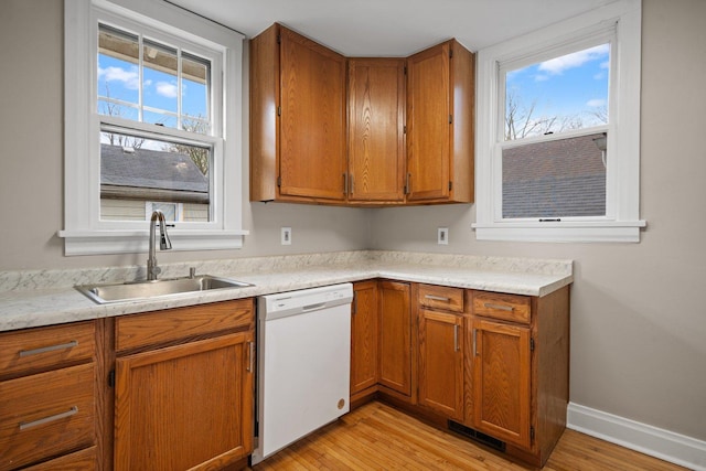 kitchen with white dishwasher, brown cabinets, and a sink
