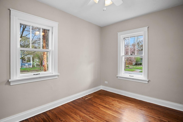 empty room with wood finished floors, a healthy amount of sunlight, baseboards, and ceiling fan