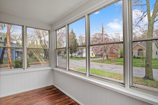 unfurnished sunroom with wood finished floors, wood walls, and plenty of natural light