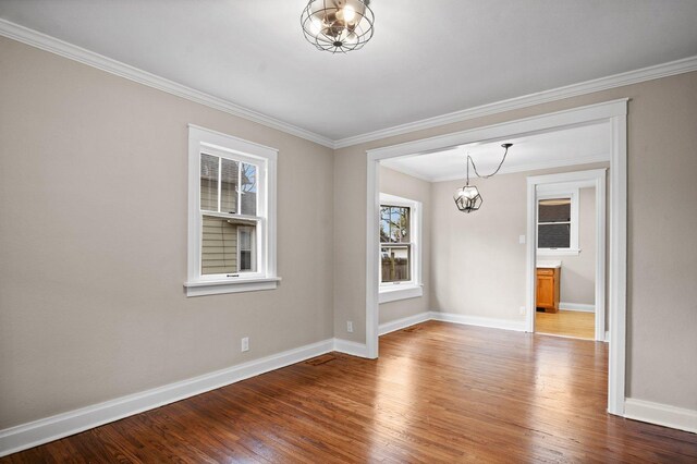 interior space with baseboards, crown molding, wood finished floors, and a chandelier