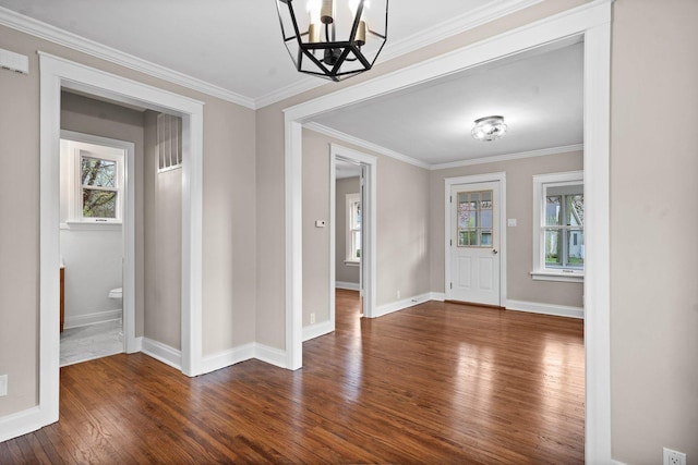 foyer entrance with baseboards, an inviting chandelier, dark wood-type flooring, and crown molding