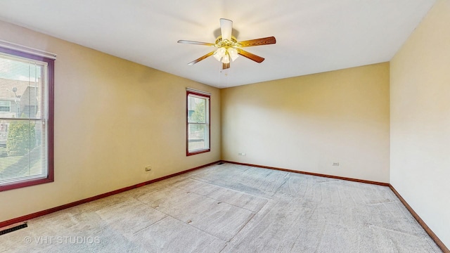 carpeted spare room featuring baseboards and a ceiling fan