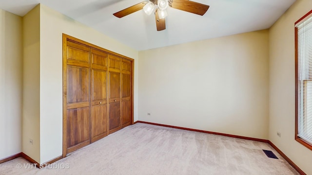 unfurnished bedroom featuring a closet, baseboards, light carpet, and a ceiling fan