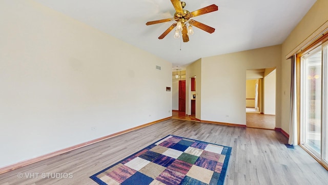 spare room featuring light wood-type flooring, plenty of natural light, ceiling fan, and baseboards