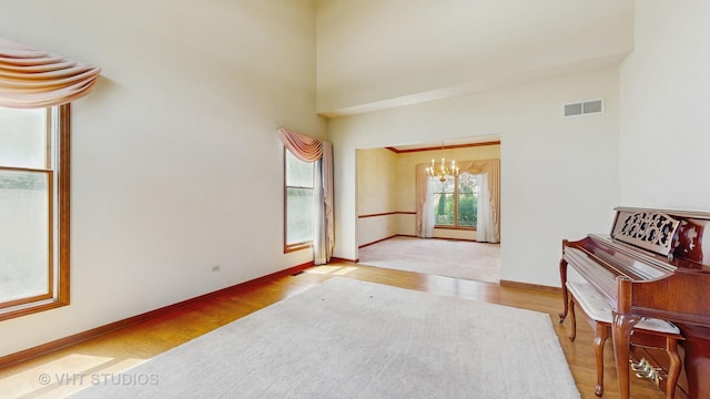 unfurnished room featuring a chandelier, wood finished floors, baseboards, and a towering ceiling