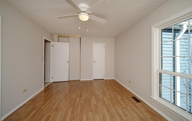 4150 Brentwood Ln, Waukegan, IL 60087 - unfurnished bedroom featuring light wood-style floors, a textured ceiling, multiple windows, and baseboards