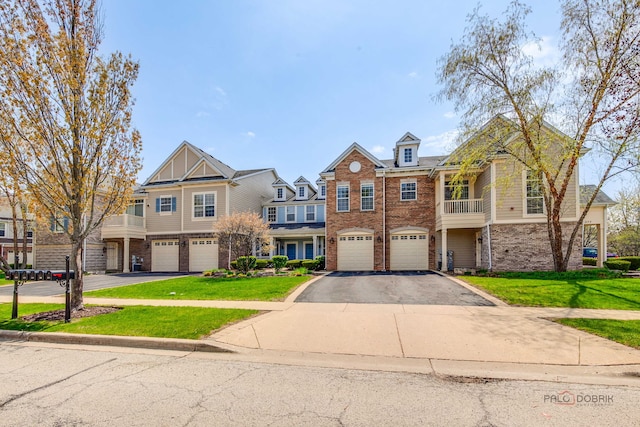 view of property with brick siding, an attached garage, driveway, and a front lawn