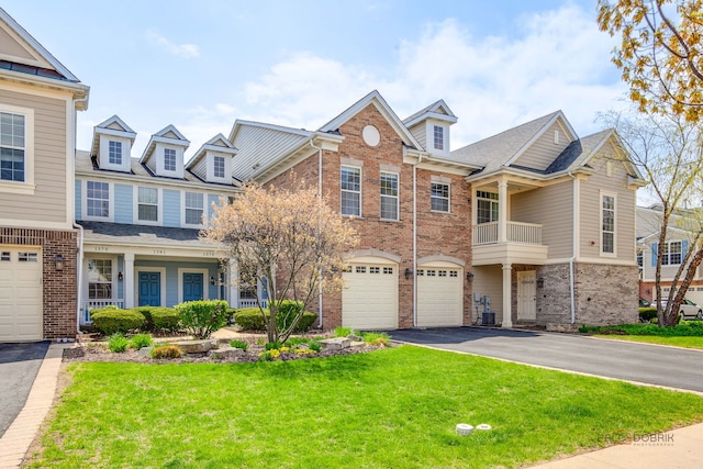 multi unit property featuring a garage, a front yard, driveway, and brick siding