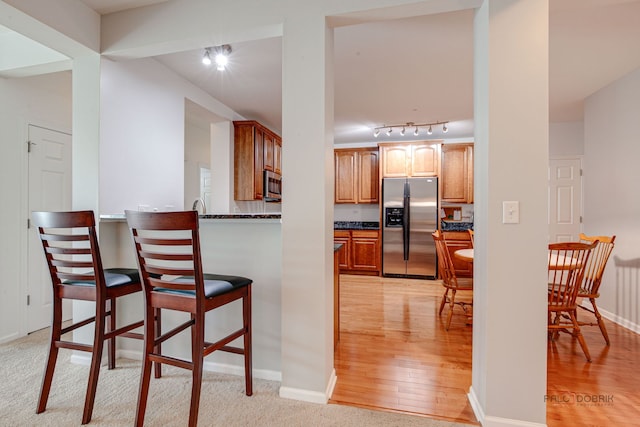 kitchen with rail lighting, light wood finished floors, a kitchen bar, and stainless steel appliances