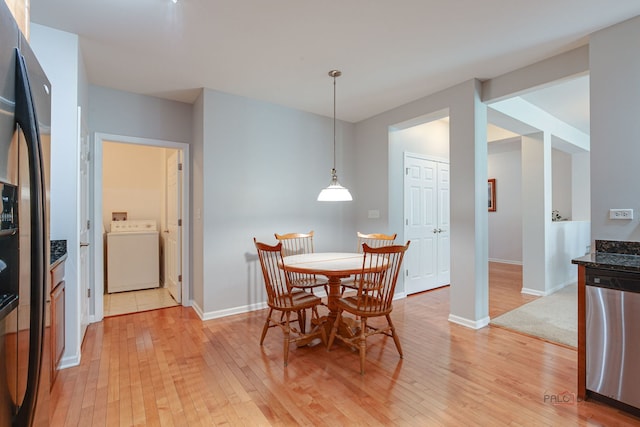dining room featuring baseboards, light wood-type flooring, and washer / clothes dryer
