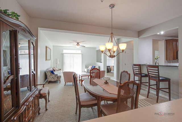 dining space featuring light colored carpet and ceiling fan with notable chandelier