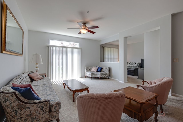 living room with baseboards, ceiling fan, and light carpet
