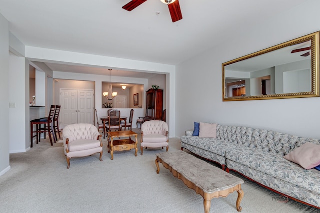 carpeted living area featuring baseboards and ceiling fan with notable chandelier