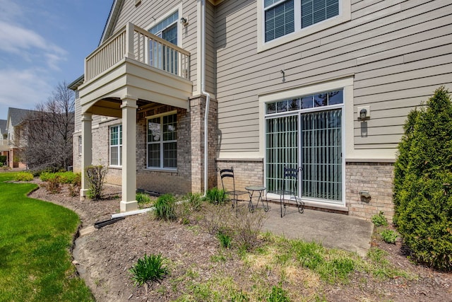 entrance to property with brick siding and a balcony