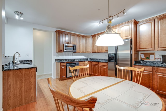 kitchen with a sink, brown cabinetry, stainless steel appliances, and light wood finished floors