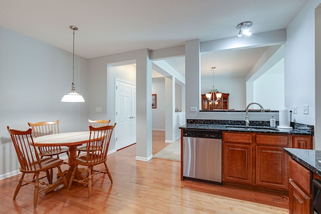 kitchen featuring dark stone counters, light wood-type flooring, a sink, and dishwasher