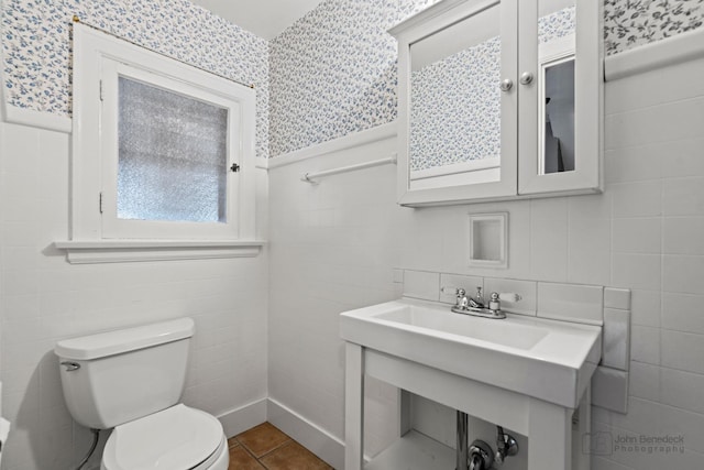 bathroom with toilet, wallpapered walls, and tile walls