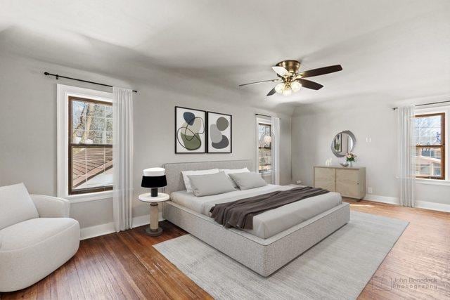 bedroom featuring ceiling fan, baseboards, wood finished floors, and multiple windows