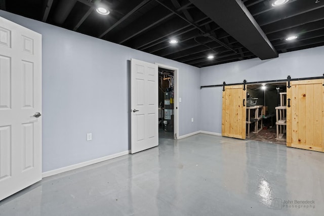 finished below grade area featuring water heater, a barn door, and baseboards