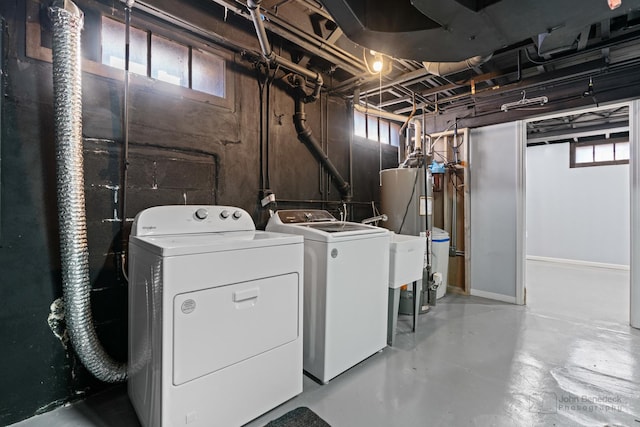 clothes washing area with separate washer and dryer, water heater, a wealth of natural light, and laundry area