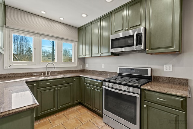 kitchen with light tile patterned floors, green cabinetry, stainless steel appliances, and a sink