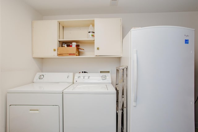 clothes washing area featuring washing machine and clothes dryer, cabinet space, and visible vents