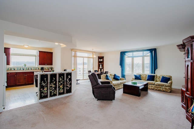 living room featuring light carpet, an inviting chandelier, and a healthy amount of sunlight