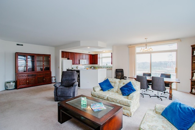 living area featuring visible vents, light colored carpet, and an inviting chandelier