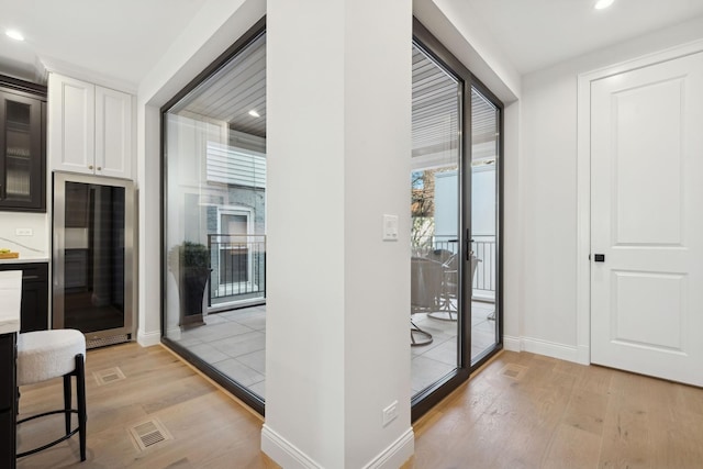 corridor featuring light wood-style floors, baseboards, and recessed lighting