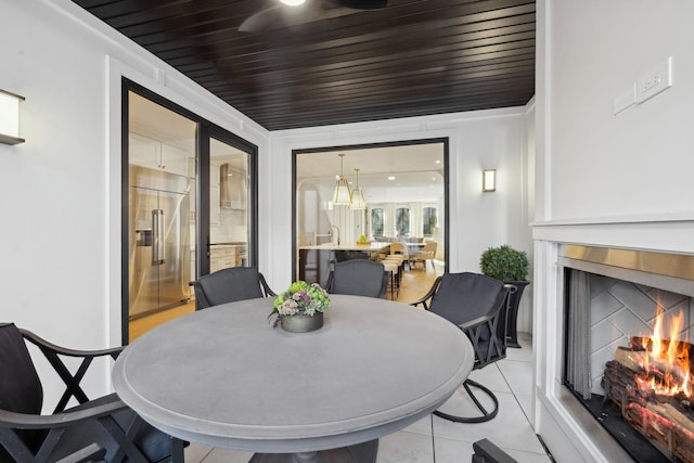 dining room featuring a warm lit fireplace and light tile patterned flooring
