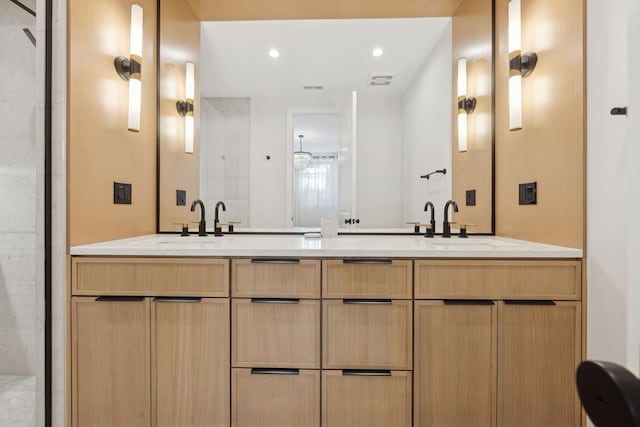 bathroom with a tile shower, double vanity, and recessed lighting
