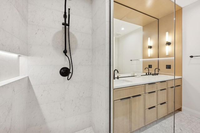 full bathroom with double vanity, tiled shower, and baseboards