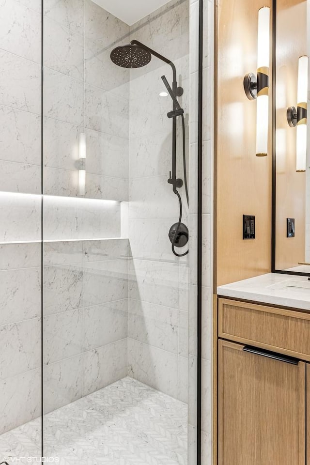 bathroom with a tile shower and vanity