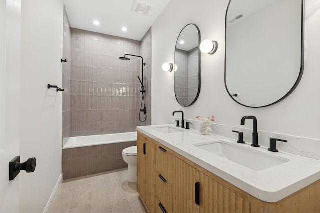bathroom featuring toilet, recessed lighting, baseboards, double vanity, and tiled shower / bath combo