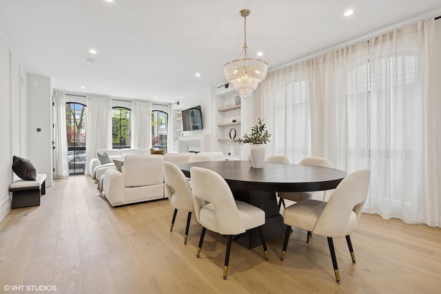 dining room featuring a chandelier, light wood-type flooring, recessed lighting, and built in shelves