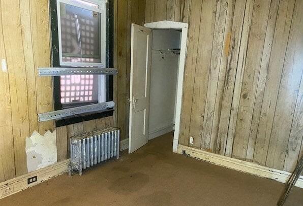 6954 S Honore St, Chicago, IL 60636 - spare room featuring carpet, wood walls, and radiator heating unit