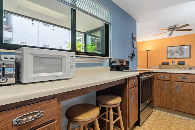 330 W Miner St Unit 1B, Arlington Heights, IL 60005 - kitchen with stainless steel electric stove, white microwave, brown cabinets, a ceiling fan, and light countertops