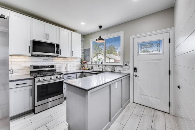 1325 Lincoln St, North Chicago, IL 60064 - kitchen featuring stainless steel appliances, a sink, a peninsula, backsplash, and white cabinetry