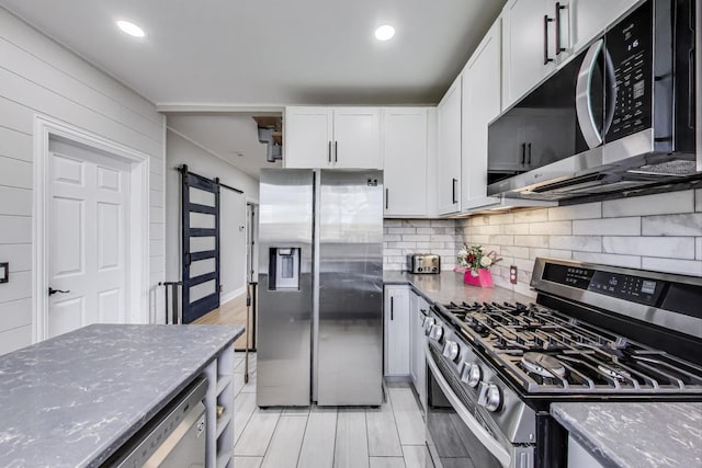 1325 Lincoln St, North Chicago, IL 60064 - kitchen with appliances with stainless steel finishes, dark stone countertops, a barn door, tasteful backsplash, and white cabinets
