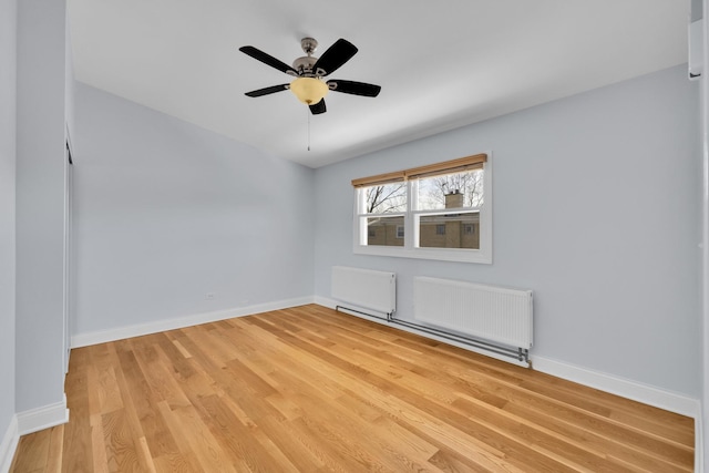 spare room with radiator, baseboards, and light wood-style floors