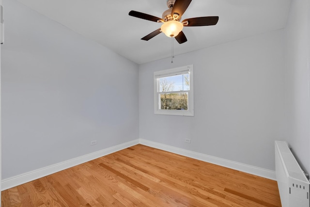 unfurnished room featuring radiator, baseboards, light wood-style floors, and ceiling fan