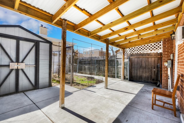 view of patio with an outdoor structure, a storage unit, and fence