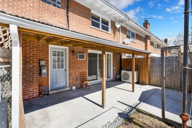 back of house with a chimney, fence, brick siding, a patio, and ac unit