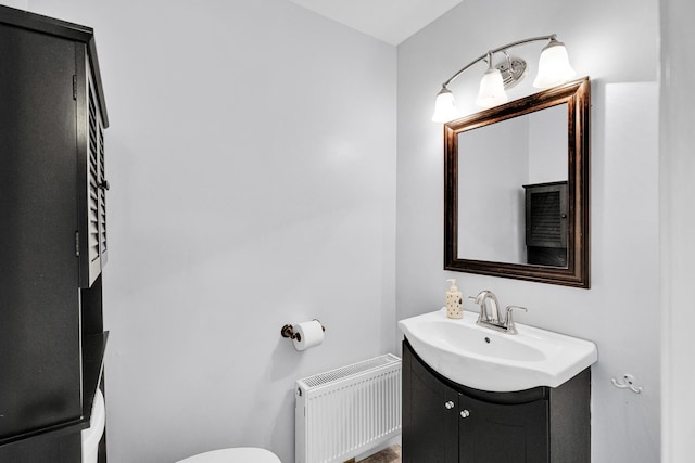 half bath with toilet, vanity, and radiator