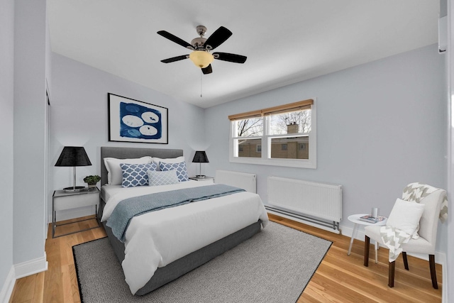 bedroom featuring radiator heating unit, baseboards, and light wood-type flooring