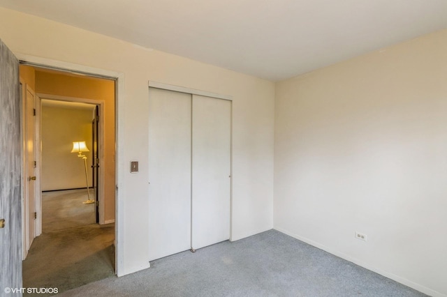 unfurnished bedroom featuring baseboards, carpet, and a closet