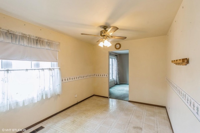 unfurnished room featuring baseboards, light floors, ceiling fan, and visible vents
