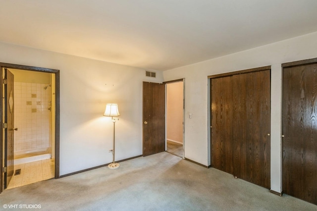 unfurnished bedroom with carpet flooring, connected bathroom, two closets, baseboards, and visible vents