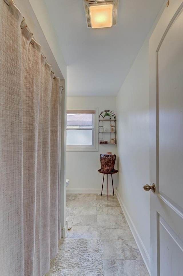 hallway featuring vaulted ceiling and baseboards